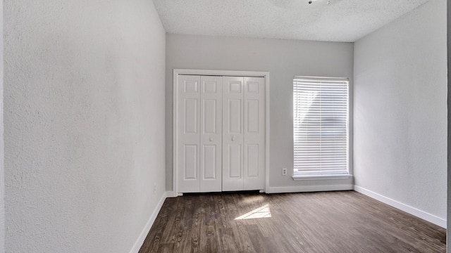 unfurnished bedroom featuring a textured ceiling, dark wood-type flooring, and a closet