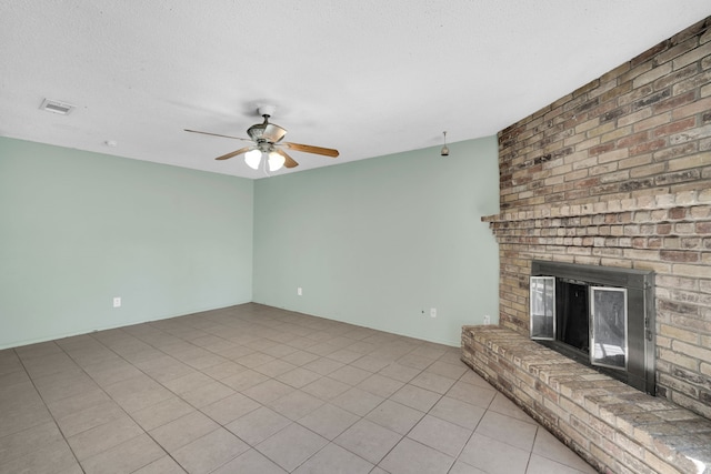 unfurnished living room with ceiling fan, a textured ceiling, light tile patterned floors, and a fireplace