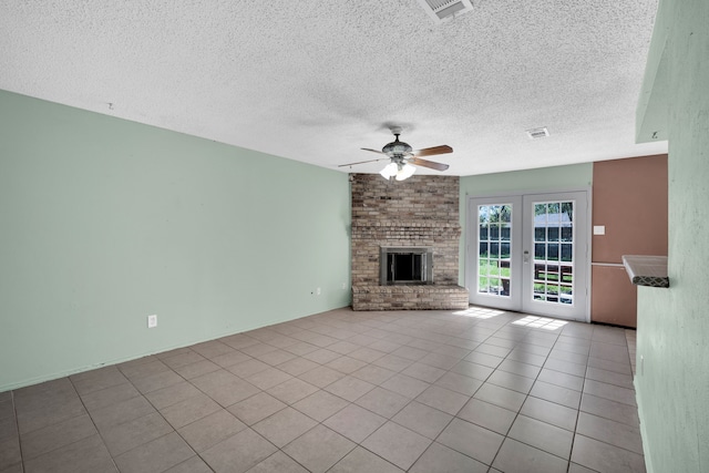 unfurnished living room with a textured ceiling, french doors, a fireplace, light tile patterned flooring, and ceiling fan