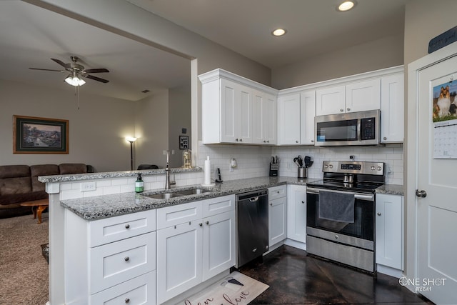 kitchen with backsplash, kitchen peninsula, sink, appliances with stainless steel finishes, and white cabinets