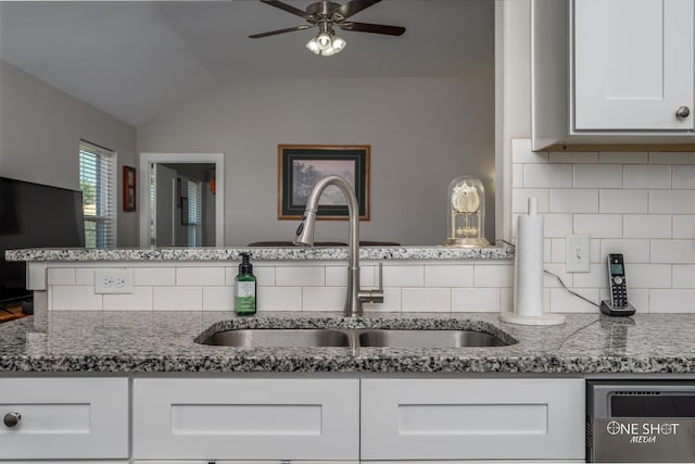 kitchen featuring stone counters, white cabinetry, lofted ceiling, and sink