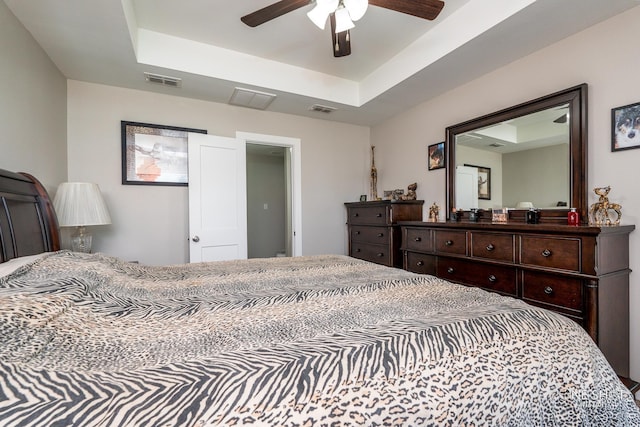 bedroom with ceiling fan and a tray ceiling