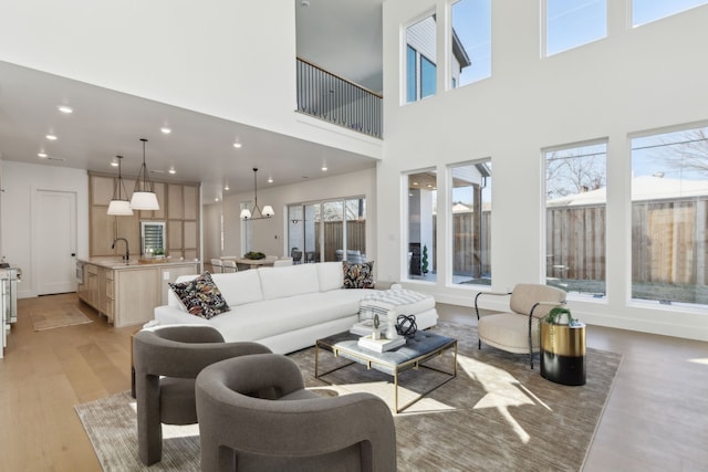 living room with sink, an inviting chandelier, and light hardwood / wood-style flooring