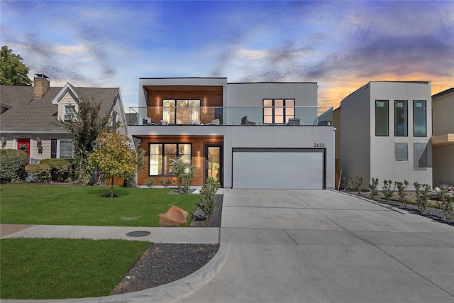 modern home featuring a balcony, a yard, and a garage