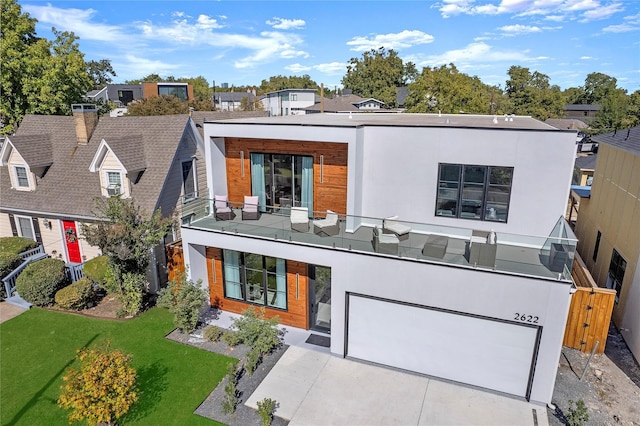 rear view of house featuring a balcony, a yard, and a garage