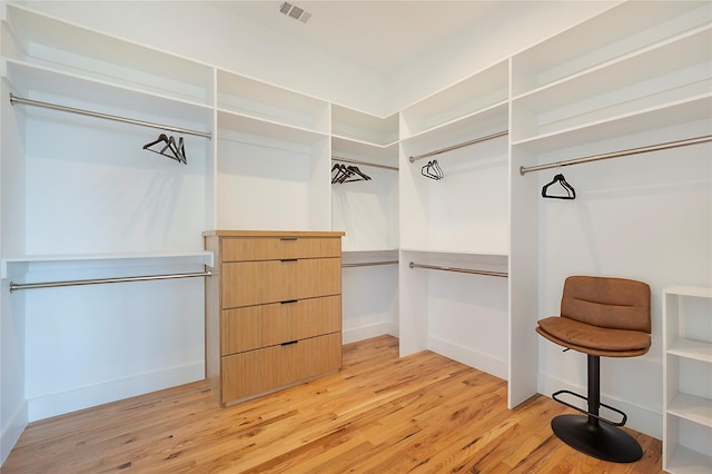 walk in closet with light hardwood / wood-style floors