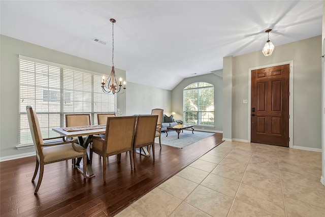 dining area featuring visible vents, baseboards, lofted ceiling, an inviting chandelier, and light wood-style floors