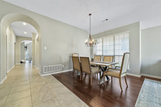 tiled dining room with vaulted ceiling and a chandelier