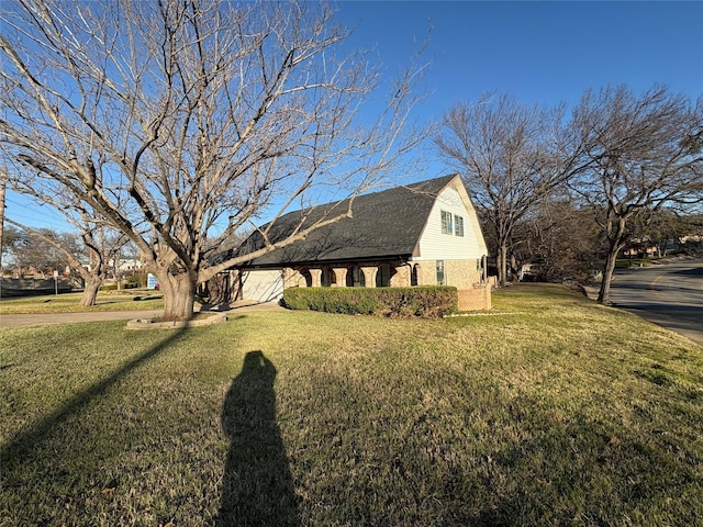 view of side of home featuring a yard, a gambrel roof, brick siding, and roof with shingles