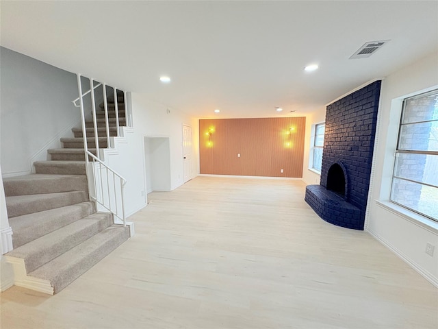 living room with a healthy amount of sunlight, light wood-type flooring, and a brick fireplace