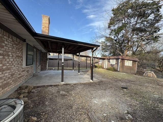 view of patio with an outbuilding and fence