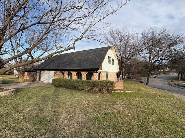 view of side of property featuring a gambrel roof, a lawn, concrete driveway, an attached garage, and brick siding