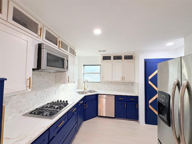 kitchen with stainless steel appliances, decorative backsplash, blue cabinetry, white cabinets, and sink