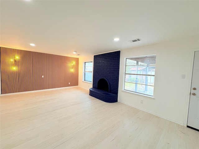 unfurnished living room featuring a brick fireplace and light hardwood / wood-style flooring