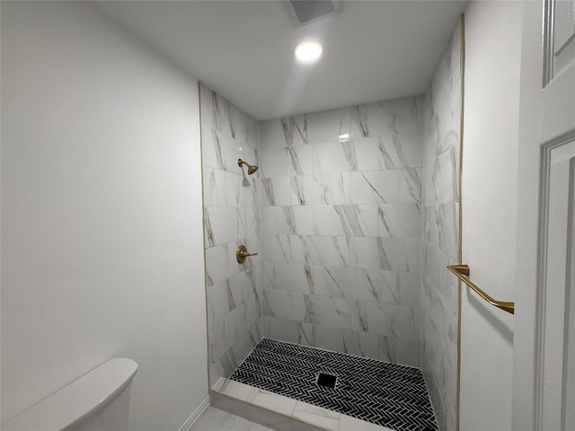 bathroom with tiled shower and toilet