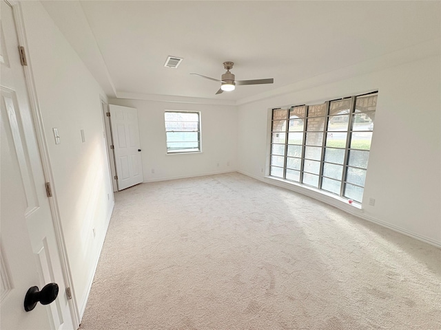 empty room featuring baseboards, light colored carpet, visible vents, and ceiling fan