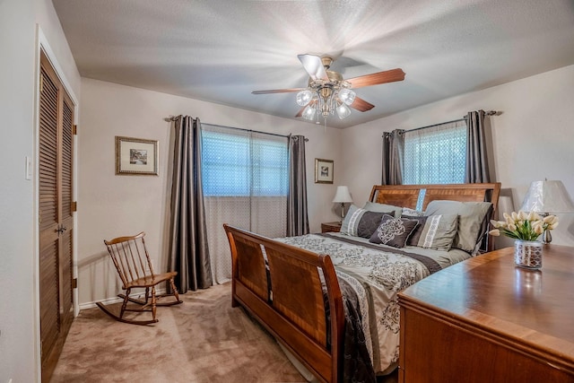 bedroom featuring ceiling fan, multiple windows, a closet, and light carpet