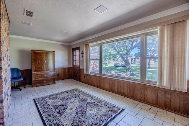 interior space with a textured ceiling, ornamental molding, and wooden walls