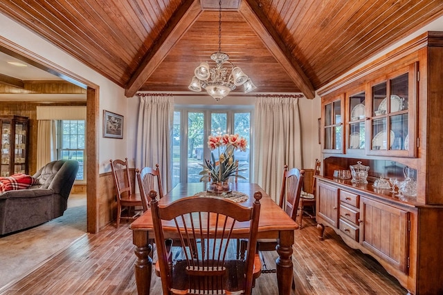 dining area with beam ceiling, light wood-type flooring, wood ceiling, and an inviting chandelier