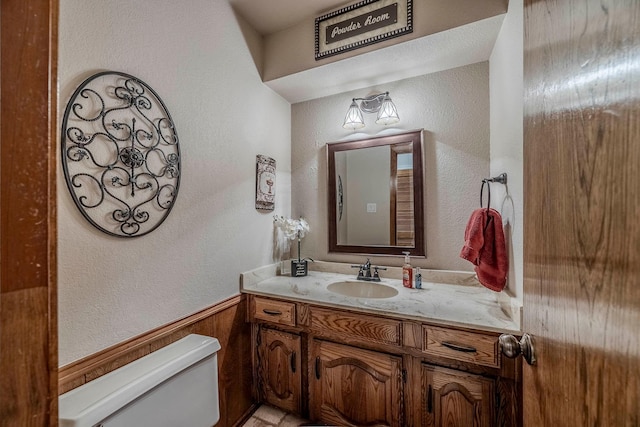 bathroom featuring toilet, vanity, and wood walls