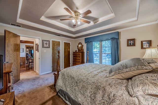 bedroom featuring ceiling fan, ornamental molding, a raised ceiling, and carpet floors