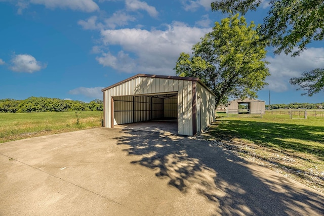 garage with a rural view and a yard