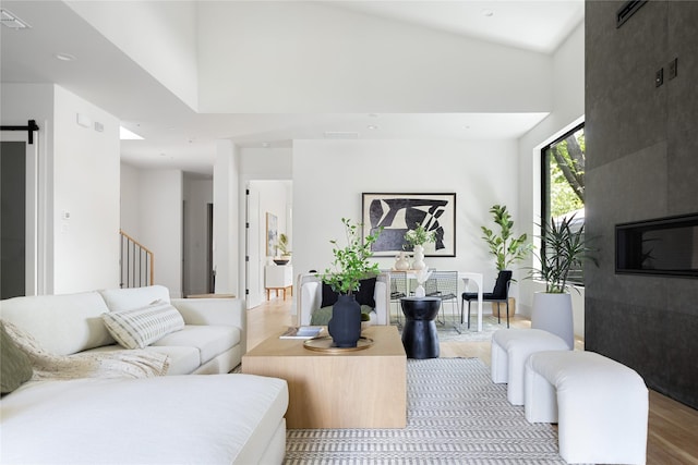 living room with light hardwood / wood-style floors, a high ceiling, and a barn door