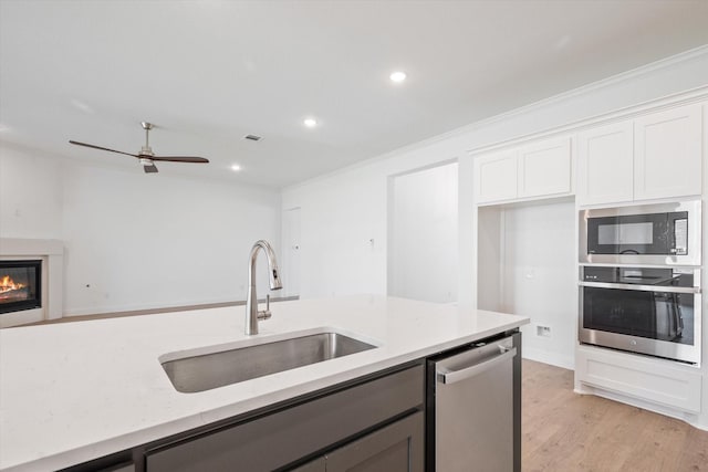 kitchen featuring light stone countertops, white cabinetry, stainless steel appliances, sink, and light hardwood / wood-style flooring