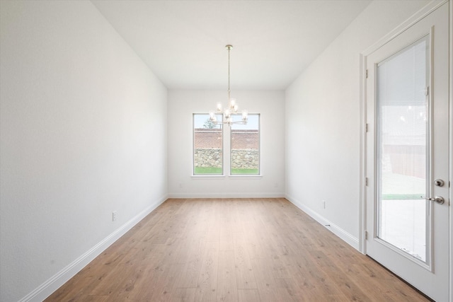 unfurnished dining area with light wood-type flooring and an inviting chandelier