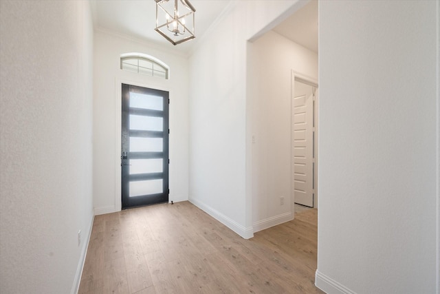 entryway featuring crown molding, a chandelier, and light hardwood / wood-style floors