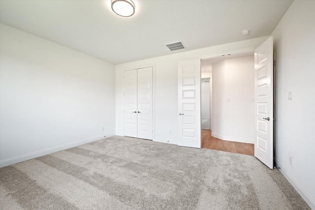 unfurnished bedroom featuring light carpet and a closet