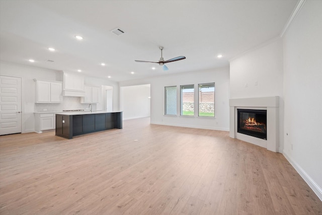 unfurnished living room with ceiling fan, light hardwood / wood-style flooring, and crown molding