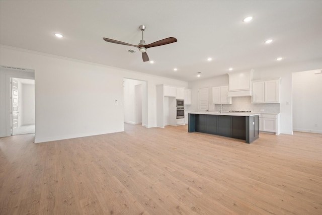 unfurnished living room with ceiling fan, ornamental molding, and light hardwood / wood-style floors