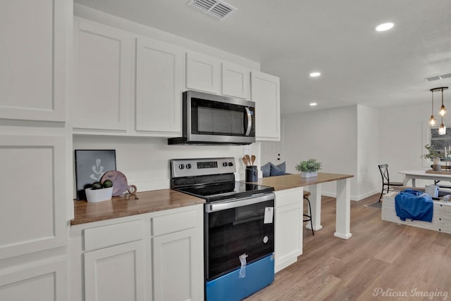 kitchen with stainless steel appliances, pendant lighting, white cabinets, and butcher block countertops