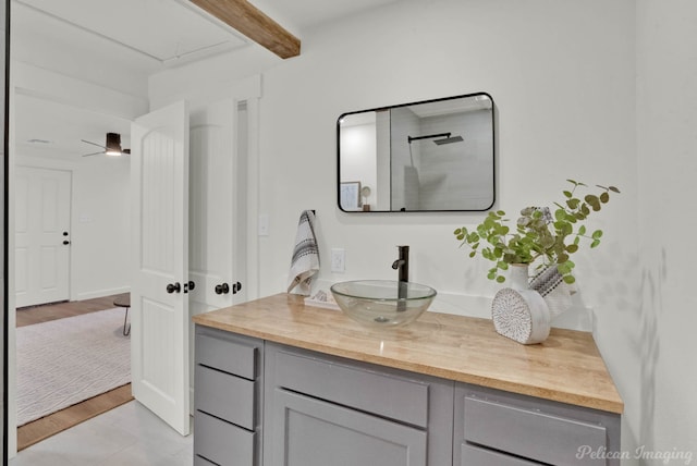 bathroom featuring ceiling fan, vanity, and beamed ceiling