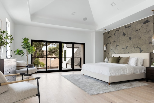 bedroom with a raised ceiling, access to exterior, a high ceiling, and hardwood / wood-style floors