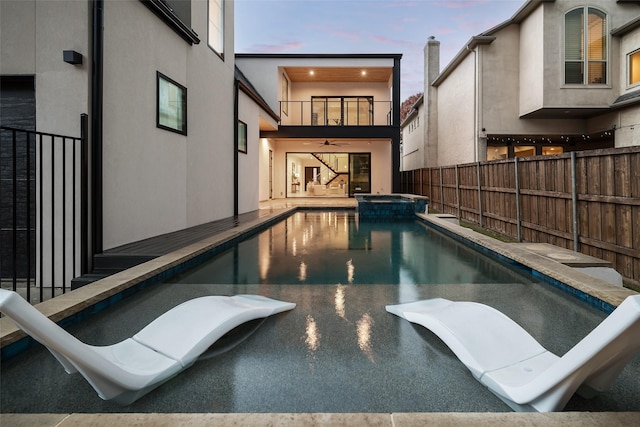 pool at dusk with an in ground hot tub and ceiling fan