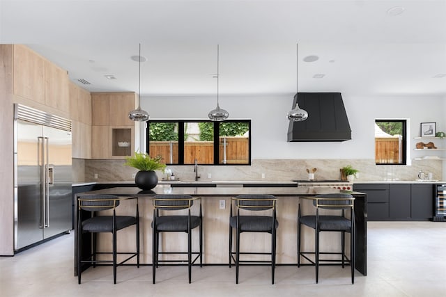 kitchen featuring a kitchen bar, stainless steel built in refrigerator, a center island, and custom exhaust hood