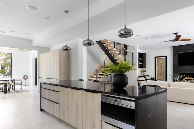 kitchen with ceiling fan, light brown cabinetry, wall oven, and pendant lighting