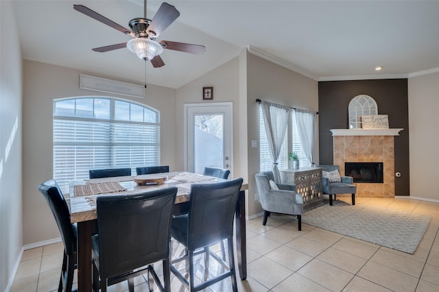 dining area with vaulted ceiling, ceiling fan, light tile patterned floors, and a tiled fireplace