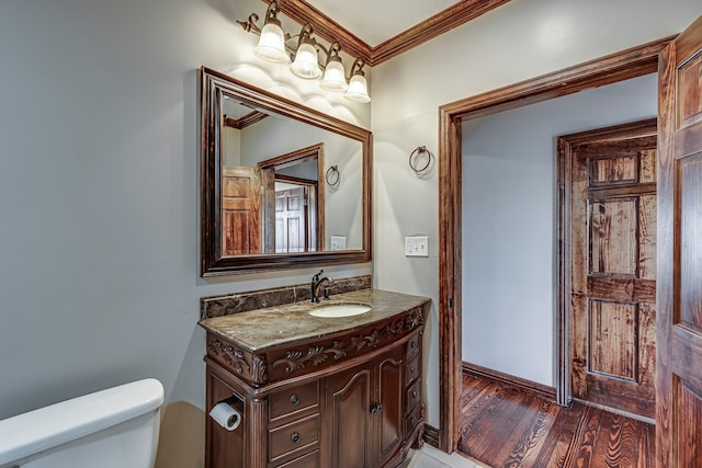 bathroom with toilet, vanity, ornamental molding, and hardwood / wood-style flooring