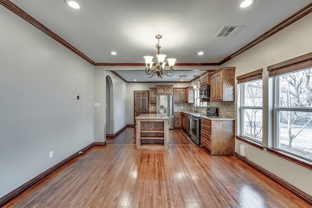 kitchen with appliances with stainless steel finishes, backsplash, a center island, hanging light fixtures, and sink