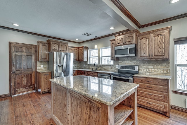 kitchen featuring a kitchen island, wood-type flooring, sink, ornamental molding, and stainless steel appliances