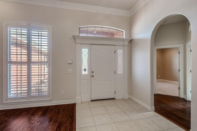 tiled foyer featuring a wealth of natural light and crown molding