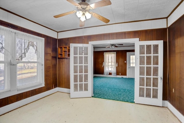 empty room featuring ornamental molding, wood walls, and french doors