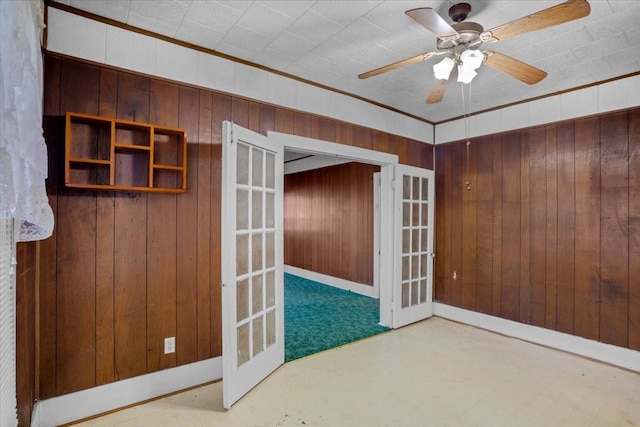 interior space with crown molding, french doors, wood walls, and ceiling fan