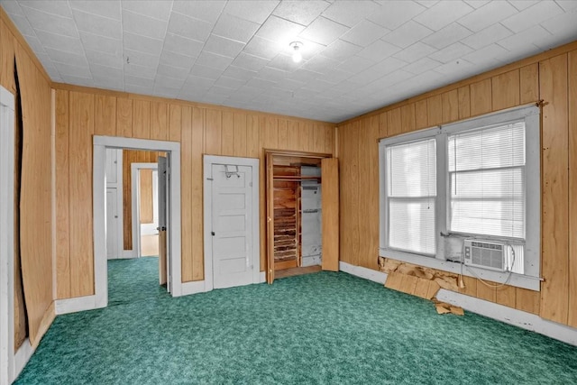 unfurnished bedroom featuring dark carpet, a closet, cooling unit, and wooden walls