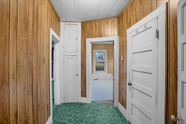 hall with dark colored carpet and wooden walls