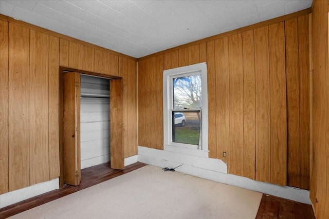 unfurnished bedroom featuring a closet and wooden walls