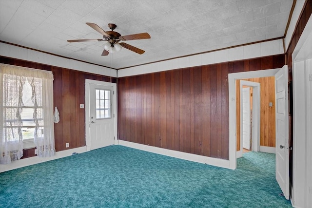 carpeted empty room with ceiling fan, crown molding, and plenty of natural light